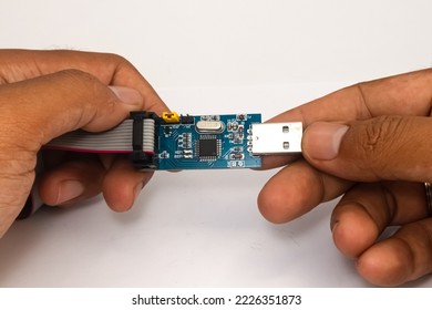 An AVR microcontroller USB downloader held in two hands.