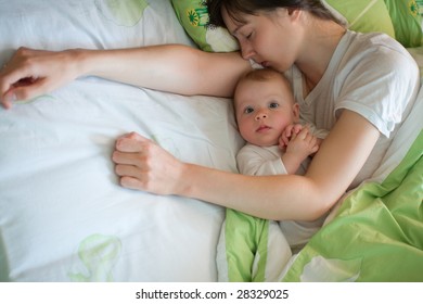 Awake Baby With Sleeping Mom In A Bed