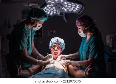 Awake Patient Screaming While Medics Providing Surgery In A Hospital.