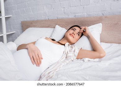 Awake Pregnant Woman With Tattoo Lying In Bed