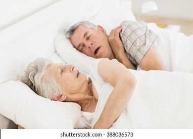Awake Senior Woman In Bed While Her Husband Is Snoring