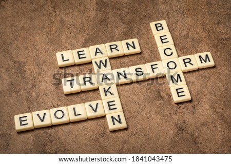 awaken, learn, evolve, transform and become crossword in ivory letter tiles against textured handmade paper, self improvement and personal development concept