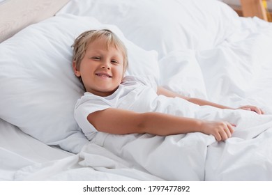 awakened boy looking at camera while lying in bed