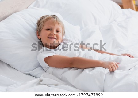 awakened boy looking at camera while lying in bed