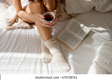 Awakened Woman Sitting on the edge of the Bed looking out the Window, bare Feet on the Floor. Side view, cropped Photo of Beautiful Female Legs. Spring rays of the sun penetrate through wooden blinds - Powered by Shutterstock