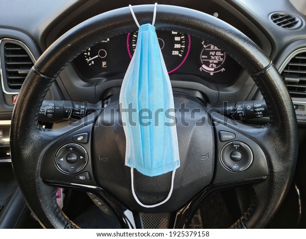 Awareness campaign concept. blue medical face mask\
on steering wheel in a\
car.