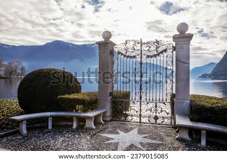 Awe view     on  lake Lugano and  park Ciani  in Lugano (free of charge). Evergreen plants and decorative gates Zdjęcia stock © 