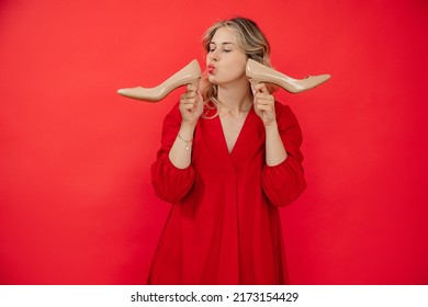 Awe young caucasian woman holding patent leather high heels beige shoes on red background with copy space, happy, kissing. Sales, shopping, formal wear - Powered by Shutterstock