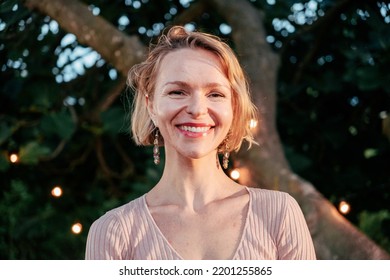 Awesom Pretty Blonde Mature Woman Looking At Camera Smiling At Sunset In The Back Yard. High Quality Photo