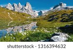 Awesome Alpine highlands in sunny day. Amazing Summer Landscape of Dolomites Alps. Wonderful Panoramic view  at Mountains Range and calm lake on foreground of Tre Cime di Lavaredo National park.