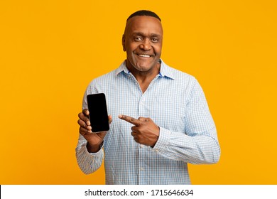 Awesome application or website. Middle aged black man showing blank cellphone screen, orange background with empty space - Powered by Shutterstock