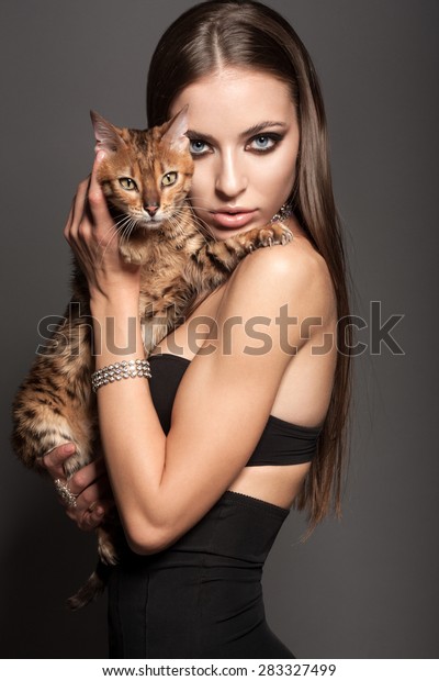 長いブルネットの自然の髪 美しい目 フル唇 スタジオでポーズをとる完璧な皮膚 ベンガル猫を抱く 美しい写真撮影 リタッチされた画像を持つ コーカサスの魅力的なセクシーなファッションモデル の写真素材 今すぐ編集