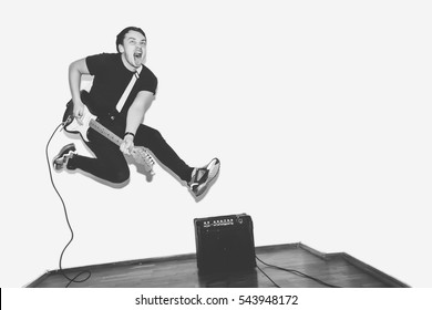 Awesome crazy fashion young rock guitar player jumps with passion in studio. Black and white toned. White background. - Powered by Shutterstock