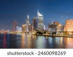 Awesome Ho Chi Minh City skyline. Night view of skyscrapers and other high-rise buildings at downtown of Ho Chi Minh City, Vietnam. Colorful city lights reflected in water of the Saigon River.