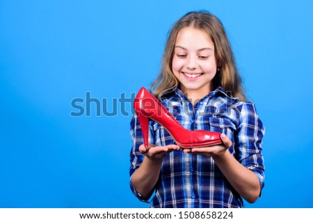 Awesome red stiletto shoes. Little fashionista kid with high heels. Female attribute. Shoes shop. Child play with moms shoes. Every girl dreaming about fashionable high heels. Glamour high heels.