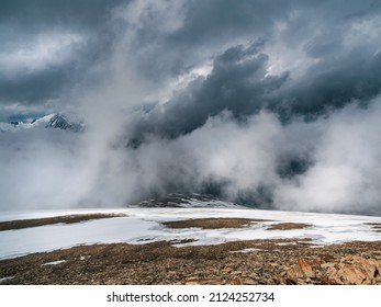 Awesome storm, a snowy atmospheric front in the mountains.Atmospheric alpine view to snow mountain range with low clouds. Scenic landscape with beautiful snow mountains in low clouds.