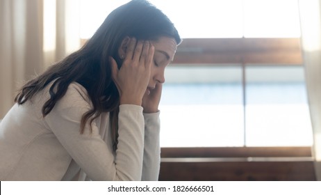 Fröhlicher Tag! Profilansicht von gestressten frustrierten Teenager Mädchen, die allein zu Hause sitzen mit geschlossenen Augen, die nach vorn umarmte Kopf haben Probleme mit Eltern, fühlen sich schlecht oder Kopfschmerzen. Leerzeichen kopieren