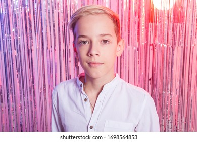 Awkward Age And Teenage Concept - Portrait Of Teen Boy At A Party. Shiny Background.