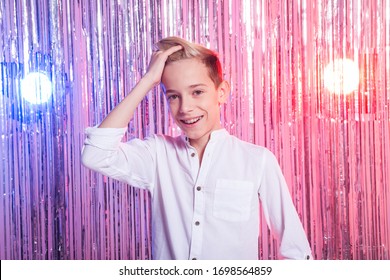 Awkward Age And Teenage Concept - Portrait Of Teen Boy At A Party. Shiny Background.