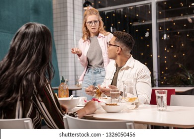 Awkward Conversation. Young Caucasian Woman Loudly Arguing With Her Confused Boyfriend While He Sitting With Another Girl.