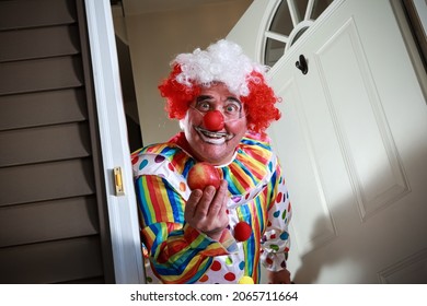 Awkward Man Dressed In A Clown Costume Handing Out Apples For Trick Or Treat On Halloween