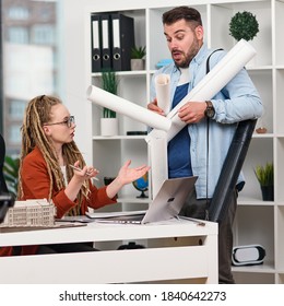 An Awkward Office Worker Scattering Drawings On The Table Of His Serious Disgruntled Female Manager.