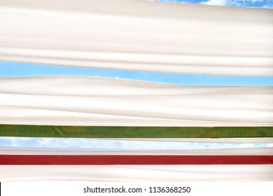 The awning over blue sky. Sky and clouds view from underneath between white canvas roof.  Copy space. Place for text.