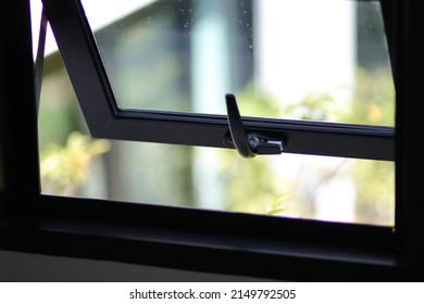 Awning window frame open, black metal detail with nature view and free space. Louver glass texture for house decor, building, real estate, property, living, hotel. Close up Aluminum casement.