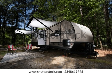 Awnings fully exented on a camper trailer in the day at a forested campsite