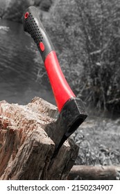 An Ax With A Red Handle Is Stabbed Into A Stump. A Cleaver Driven Into A Tree. Sawmill Work Concept. Hatchet Blade In Log