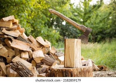 An ax sticks out in a log against   firewoods