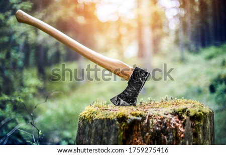 Axe cut in the chopping block in forest  background. Lumber jacks wood cutting work tool.