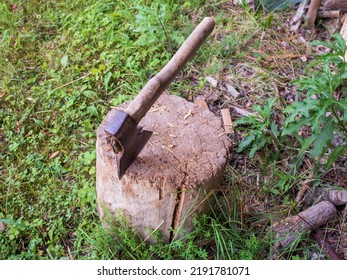 An Axe Stuck In A Old Wooden Beam In The Dark Green Grass