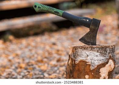 An axe will be stuck into a wooden log. Harvesting firewood for the winter season. Logging on the background of a country house. Lumber, wood-cutting tools.