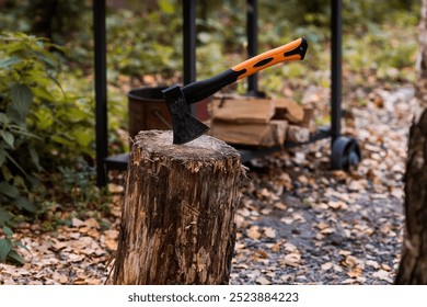An axe will be stuck into a wooden log. Harvesting firewood for the winter season. Logging on the background of the forest. Lumber, wood-cutting tools.