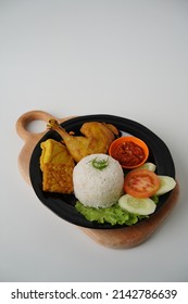 Ayam Goreng Lamongan or Pecel Ayam or Ayam Penyet is a Indonesian fried chicken with Tofu and Tempeh any fresh vegetable and chili sauce or spicy sambal. Daily asian food. On white background.