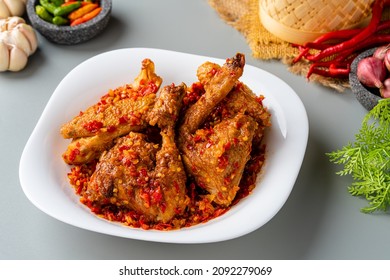 Ayam sambal balado or spicy fried chicken is Traditional food from Padang, West Sumatra. served on plate and isolated gray background.