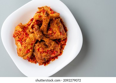 Ayam sambal balado or spicy fried chicken is Traditional food from Padang, West Sumatra. served on plate and isolated gray background.