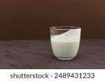 Ayran or Kefir on brown background, side view. Buttermilk made with yogurt. Fermented sour milk. Milk diet for weight loss.