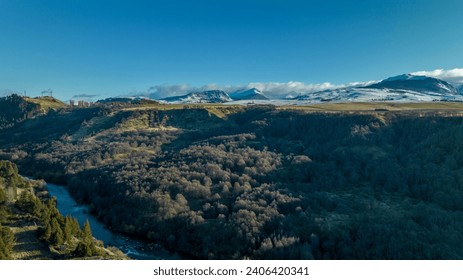 Aysen, Chile, visat of the Simpson River, crowns of native trees in the autumn period. In the background, a view from the east of the Andes Mountains and among that range of hills, Cerro La Paloma  - Powered by Shutterstock