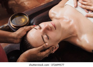 Ayurvedic Face Massage With Oil On The Wooden Table In Traditional Style Made By Asian Women. 