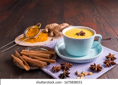 Ayurvedic golden turmeric latte milk made with turmeric and spices, on wooden background. Healthy medicine drink.