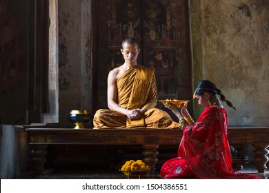 AYUTTHAYA, THAILAND – NOVEMBER 23: The monk sat with a young woman wearing a red robe offering offerings on November 23, 2017 in Ayutthaya, Thailand.