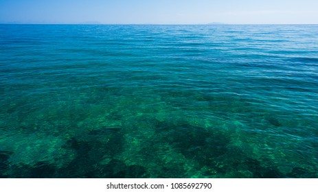 Azure blue and green water surface of Ionian sea near to the beach as background image with horizon