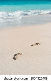 Azure Ocean Waves Rolling On The Beach With Foot Prints