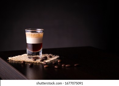 B-52 Layered Cocktail Shot On A Burlap Coaster Decorated With Fresh Roasted Coffee Beans Placed On A Bar Counter With Copy Space