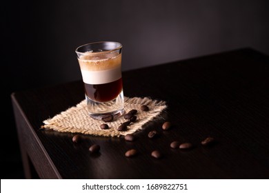 B-52 Layered Cocktail Shot On A Burlap Coaster Decorated With Fresh Roasted Coffee Beans Placed On A Bar Counter With Copy Space