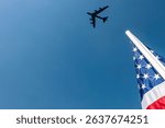 A B-52 soars above the stadium, trailing white contrails across a clear blue sky. Below, an American flag waves proudly, stirring deep patriotism and pride in the crowd during the game.