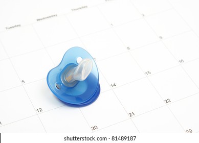 A babies pacifier on a calendar to conceptualize on many maternity ideas.
