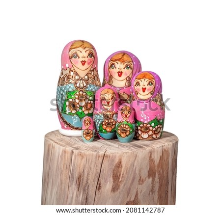 Babushka dolls arranged on wood log. Group of colorful painted Russian stacking dolls also known as Matroska doll or Russian tea dolls. Symbole of grandmother or fertility. Isolated on white.